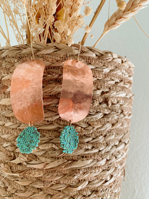 Hammered copper medallion with a turquoise-colored bead woven coin.